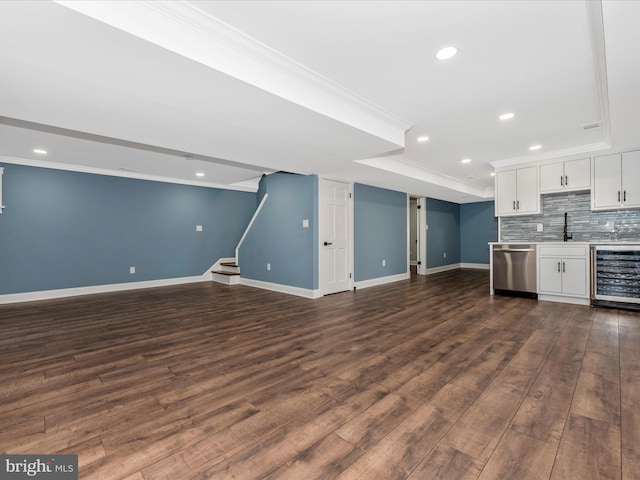 kitchen with stainless steel dishwasher, white cabinets, open floor plan, wine cooler, and ornamental molding