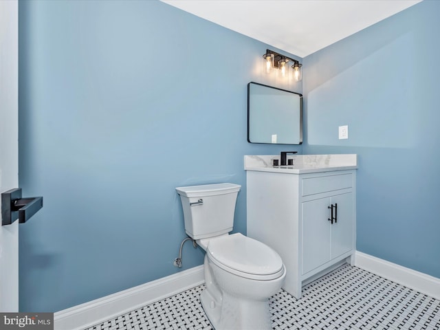 half bathroom featuring baseboards, tile patterned floors, toilet, and vanity