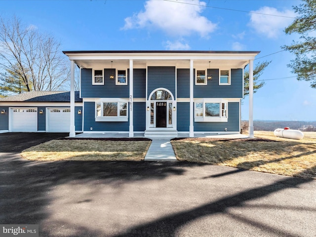 view of front of property featuring a garage, covered porch, and aphalt driveway