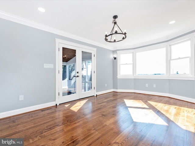 unfurnished room with french doors, visible vents, wood finished floors, an inviting chandelier, and ornamental molding