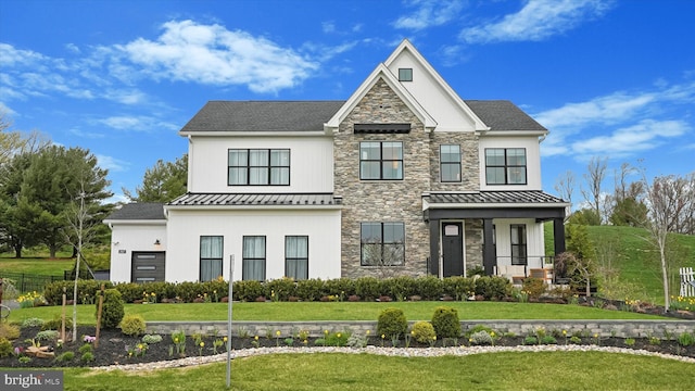 view of front of property with a standing seam roof, metal roof, a front lawn, and stone siding