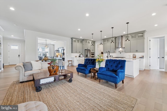 living area featuring ornamental molding, light wood-type flooring, and recessed lighting