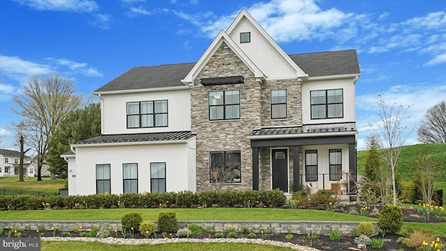 view of front of house featuring stone siding, a front yard, and a standing seam roof