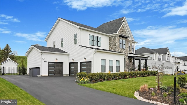 view of property exterior with a garage, aphalt driveway, fence, stone siding, and a lawn
