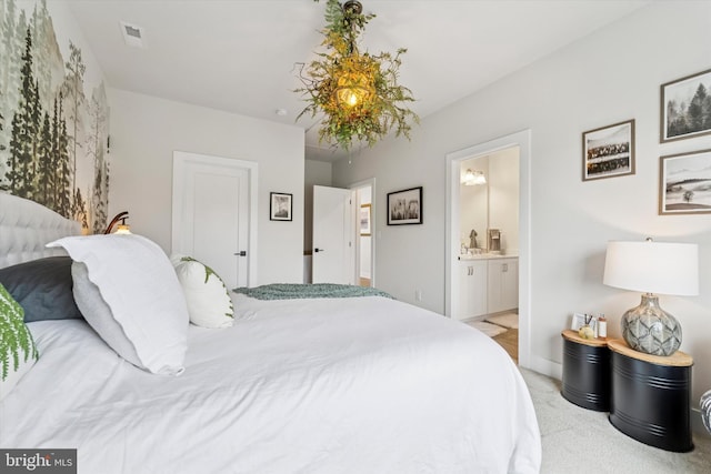 bedroom with visible vents, light carpet, and ensuite bathroom