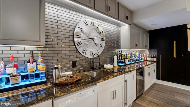 kitchen with tasteful backsplash, a sink, dishwasher, dark stone counters, and wine cooler