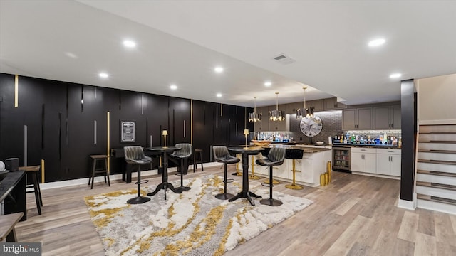 interior space with a breakfast bar area, recessed lighting, wine cooler, backsplash, and visible vents
