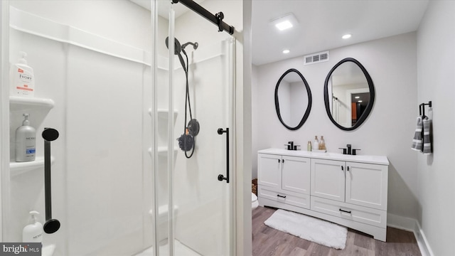 full bath with visible vents, double vanity, wood finished floors, recessed lighting, and a stall shower
