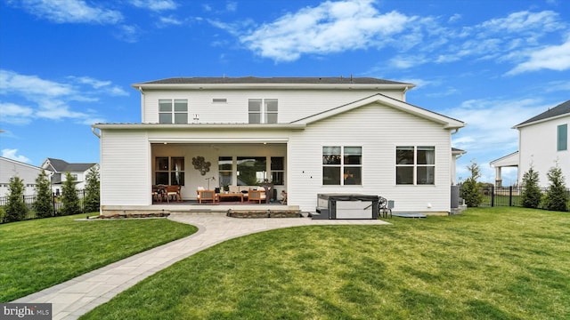 back of property with fence, a yard, a patio, and a hot tub