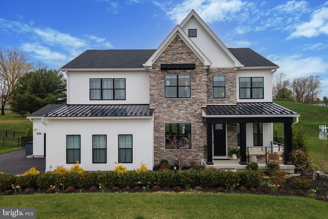 view of front of house featuring a standing seam roof, a porch, and a front lawn