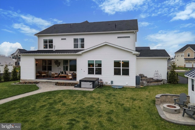 back of property with a lawn, an outdoor living space with a fire pit, a hot tub, and a patio area