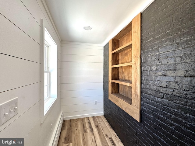 spare room featuring wood walls, wood finished floors, and built in shelves