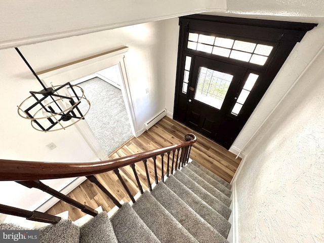 entrance foyer featuring wood finished floors, baseboards, stairs, and a baseboard heating unit