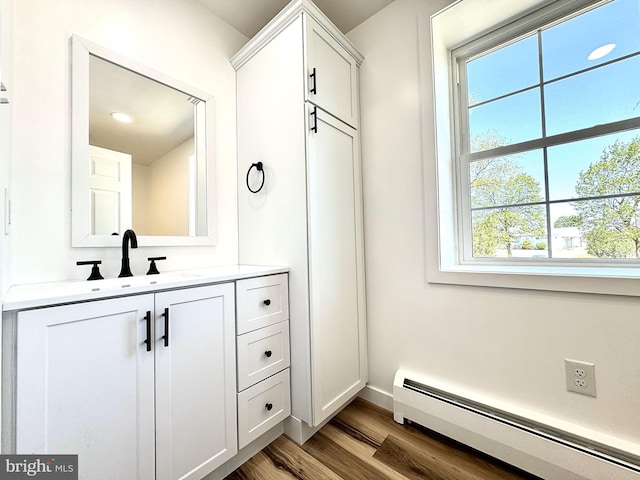 bathroom featuring vanity, a baseboard radiator, baseboards, and wood finished floors