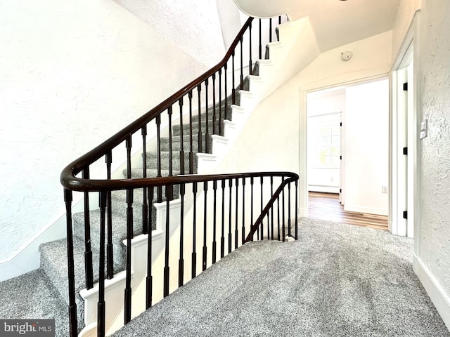 staircase featuring a textured wall and carpet flooring