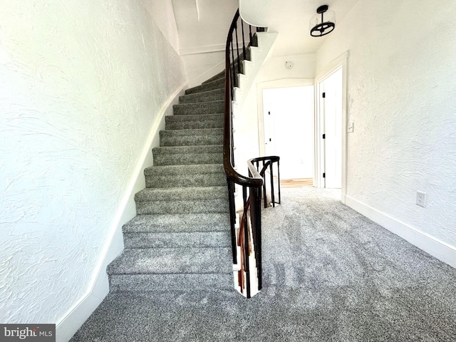stairs featuring baseboards, carpet flooring, and a textured wall