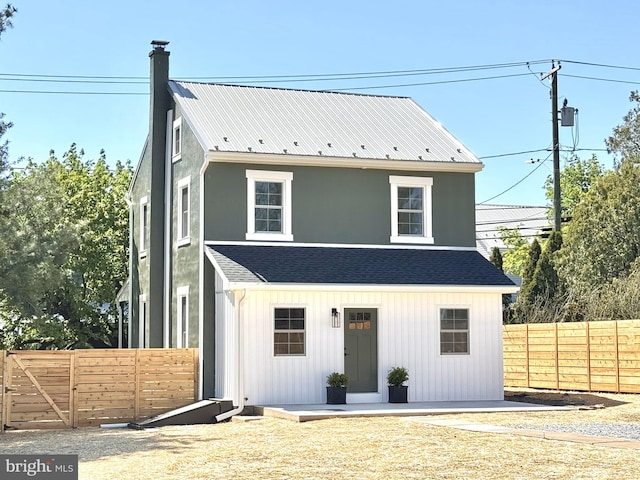 view of front of house with a fenced backyard and a chimney