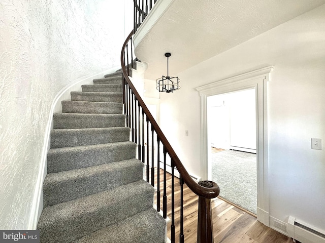 staircase featuring baseboards, a chandelier, wood finished floors, and baseboard heating