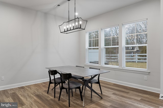 dining area featuring baseboards, wood finished floors, a chandelier, and visible vents
