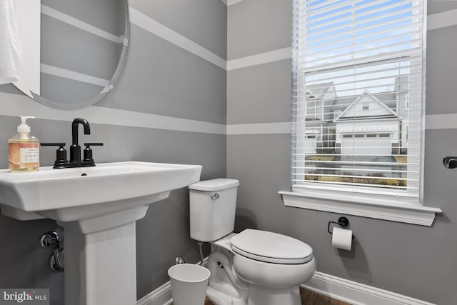 bathroom featuring baseboards, wood finished floors, and toilet