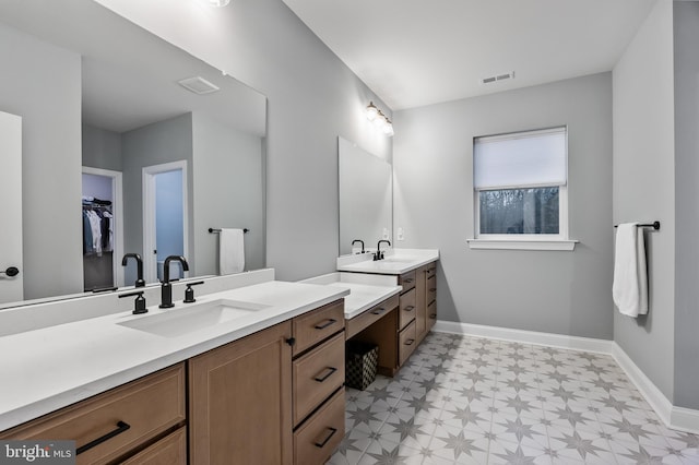 full bathroom with a sink, tile patterned floors, visible vents, and two vanities