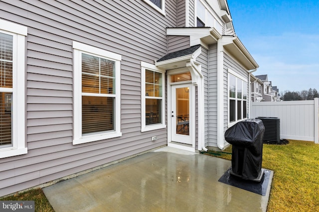 view of exterior entry featuring fence, a patio area, and central AC