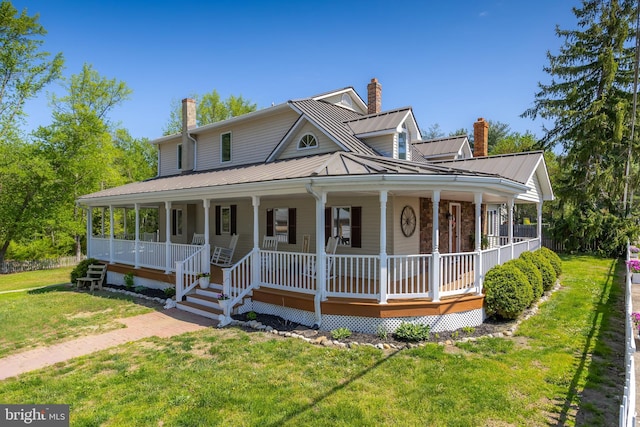 farmhouse with a front yard, a chimney, a standing seam roof, covered porch, and metal roof