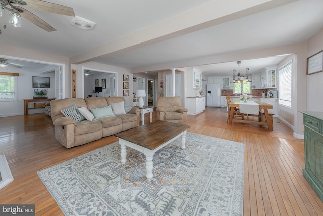 living area with baseboards, light wood-style flooring, ceiling fan, and visible vents