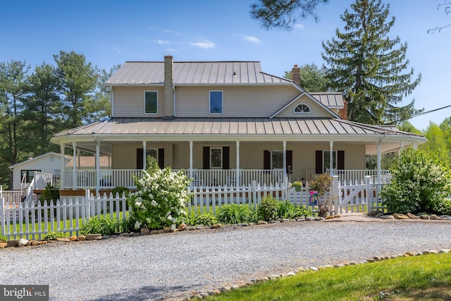 farmhouse-style home featuring metal roof, covered porch, a chimney, and a standing seam roof
