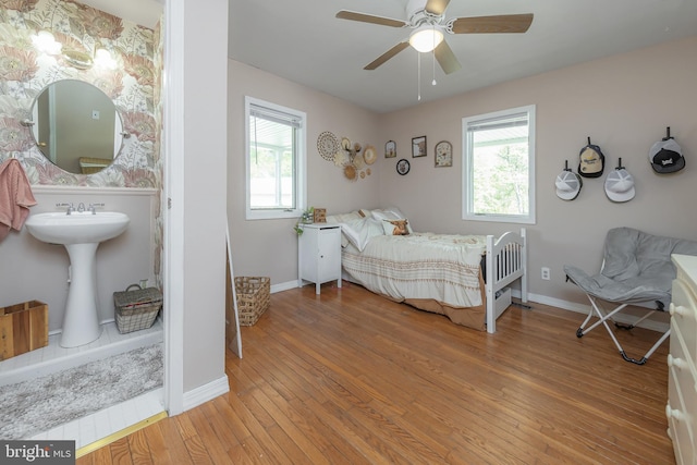 bedroom with baseboards, multiple windows, and wood finished floors