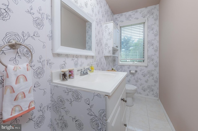 half bathroom featuring tile patterned flooring, vanity, toilet, baseboards, and wallpapered walls