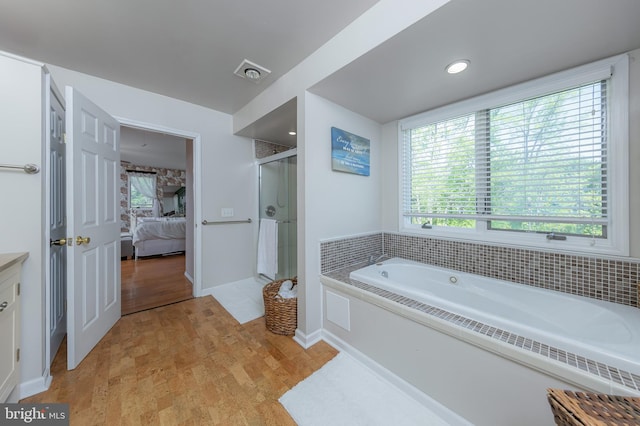 ensuite bathroom featuring a healthy amount of sunlight, ensuite bathroom, a bath, and a stall shower