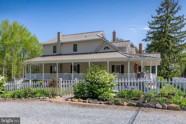 view of front facade featuring covered porch, a chimney, and fence private yard