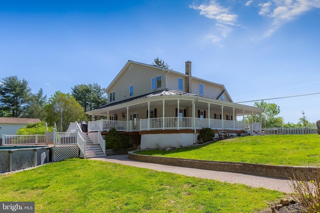 rear view of house with fence, a porch, stairway, a chimney, and a lawn