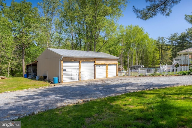 detached garage featuring fence and driveway