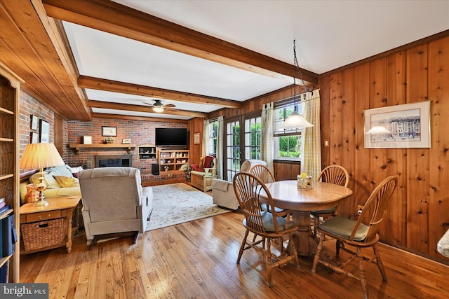 122 Tregarone Rd, Lutherville Timonium, MD 21093 - dining space with wood walls, a brick fireplace, beam ceiling, ceiling fan, and light wood finished floors