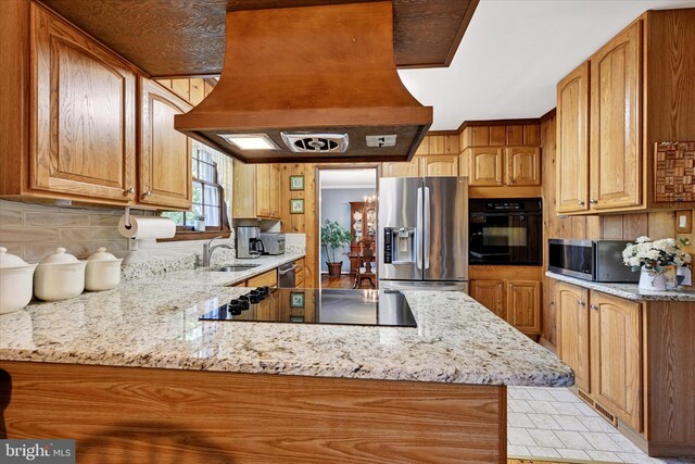 122 Tregarone Rd, Lutherville Timonium, MD 21093 - kitchen featuring a peninsula, light stone countertops, island range hood, a sink, and black appliances
