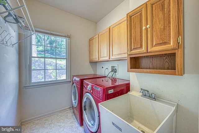 washroom featuring cabinet space, a wealth of natural light, a sink, and washing machine and clothes dryer