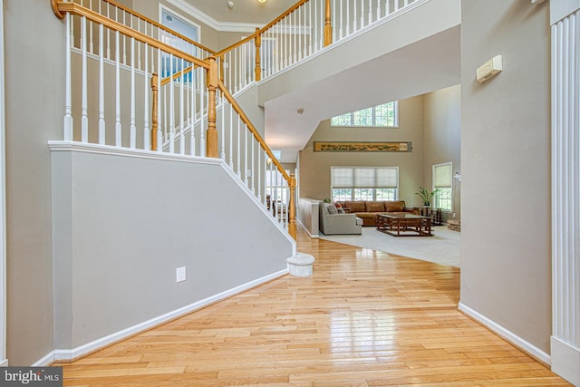 entryway featuring crown molding, wood finished floors, stairway, baseboards, and a high ceiling
