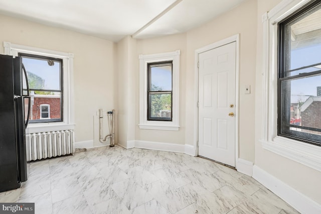 unfurnished room with baseboards, radiator heating unit, and marble finish floor