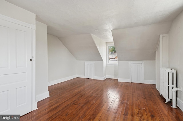 additional living space with radiator, baseboards, vaulted ceiling, and hardwood / wood-style floors