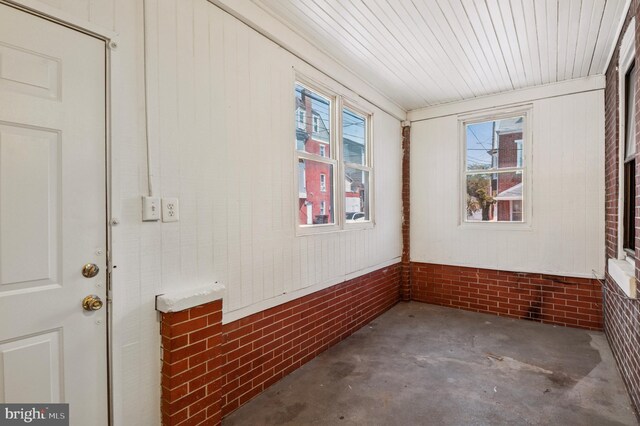 spare room featuring unfinished concrete flooring and brick wall