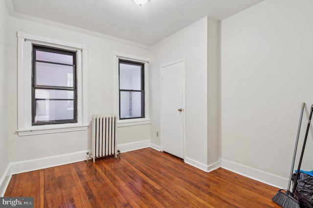 unfurnished room featuring radiator heating unit, baseboards, and hardwood / wood-style floors