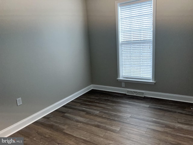 unfurnished room with visible vents, baseboards, and dark wood-style floors