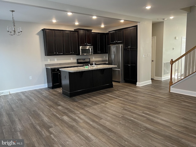 kitchen with baseboards, a kitchen breakfast bar, dark wood-style floors, and stainless steel appliances