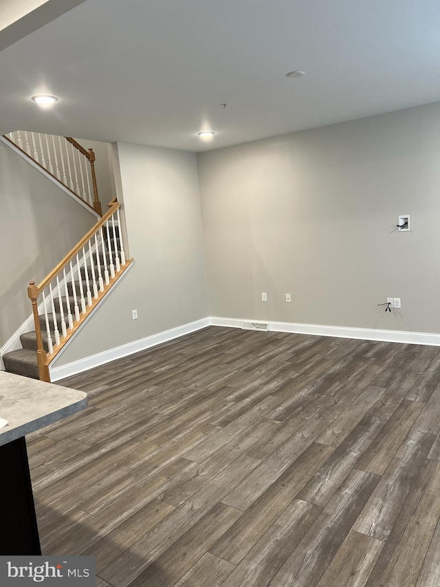 unfurnished living room with stairs, recessed lighting, baseboards, and dark wood-type flooring