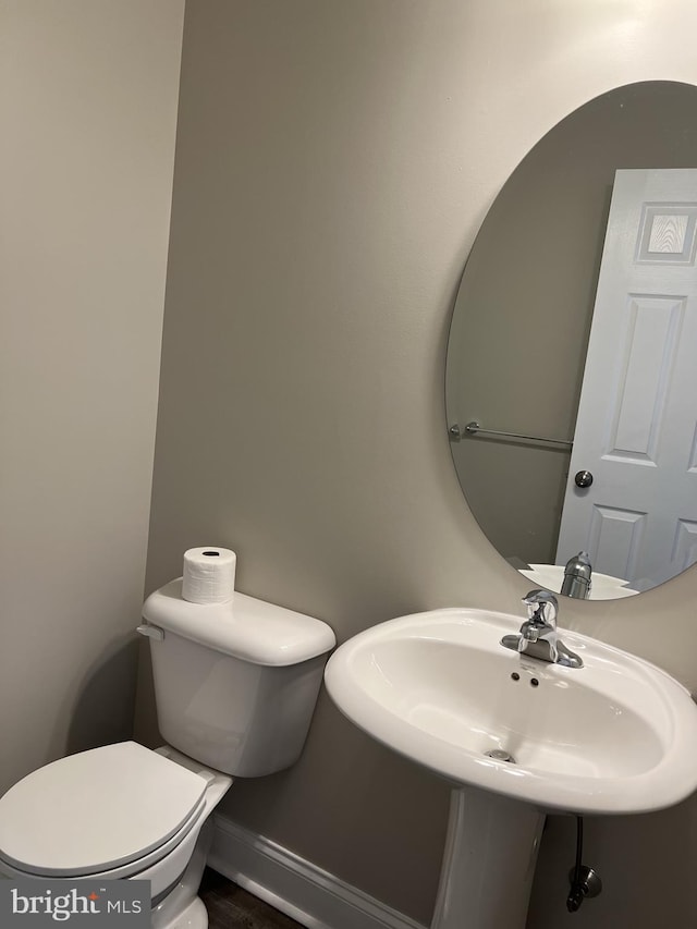 bathroom with baseboards, a sink, and toilet