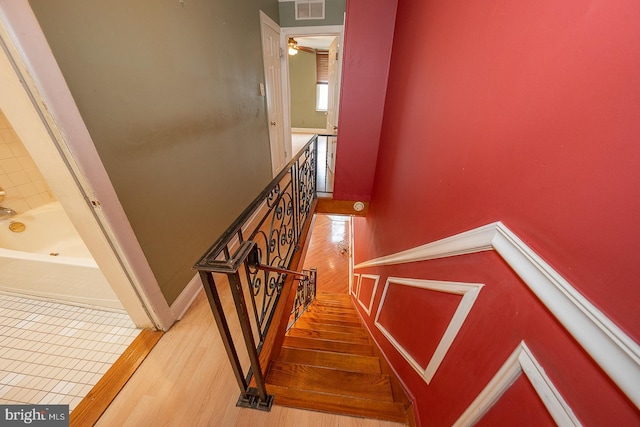staircase with a ceiling fan, wood finished floors, and visible vents