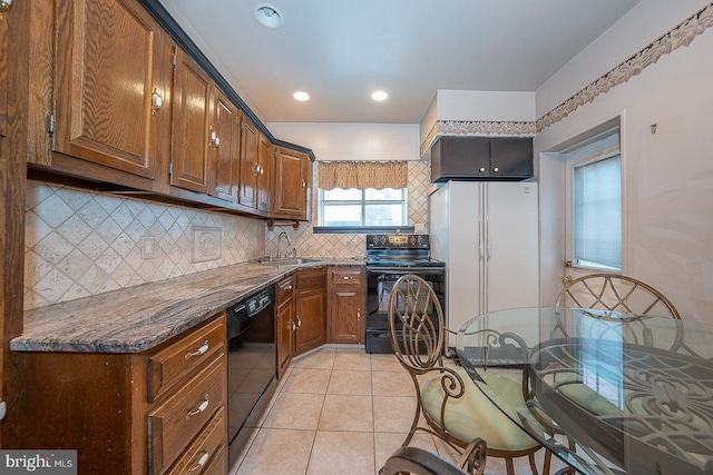 kitchen with a sink, brown cabinetry, decorative backsplash, light tile patterned floors, and black appliances