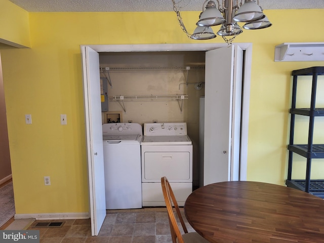laundry room featuring laundry area, visible vents, an inviting chandelier, washing machine and dryer, and baseboards